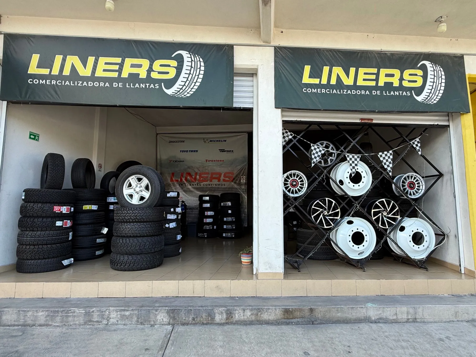 Fachada de LINERS: dos locales con letreros verdes y llantas y rines en exhibición